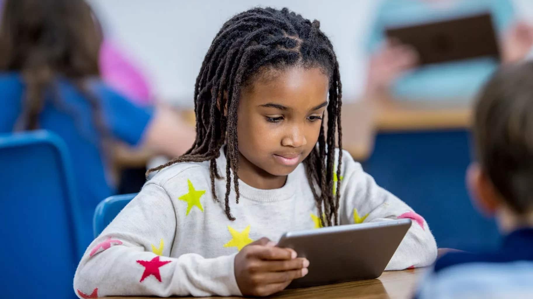 A young student working on a tablet in class
